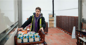 Worker picking up a crate of food items